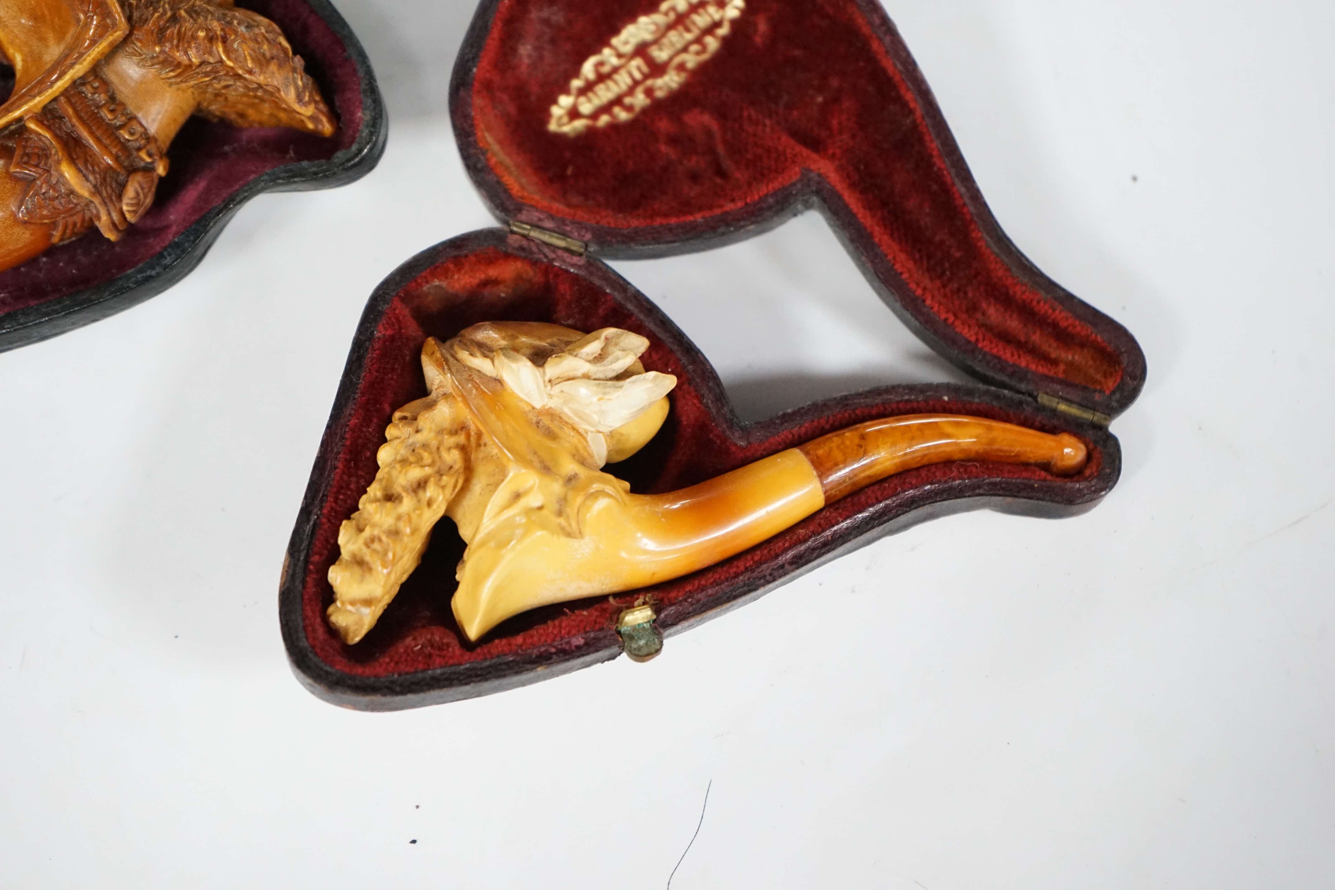 Two cased novelty Meerschaum pipes, their bowls modelled as an Arthurian knight and another a bearded man, both with amber mouthpieces, largest 16cm long